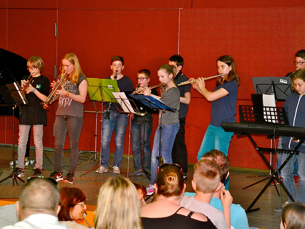 Eine Gruppe spielt Querflöte und Blasinstrumente an Notenständern.